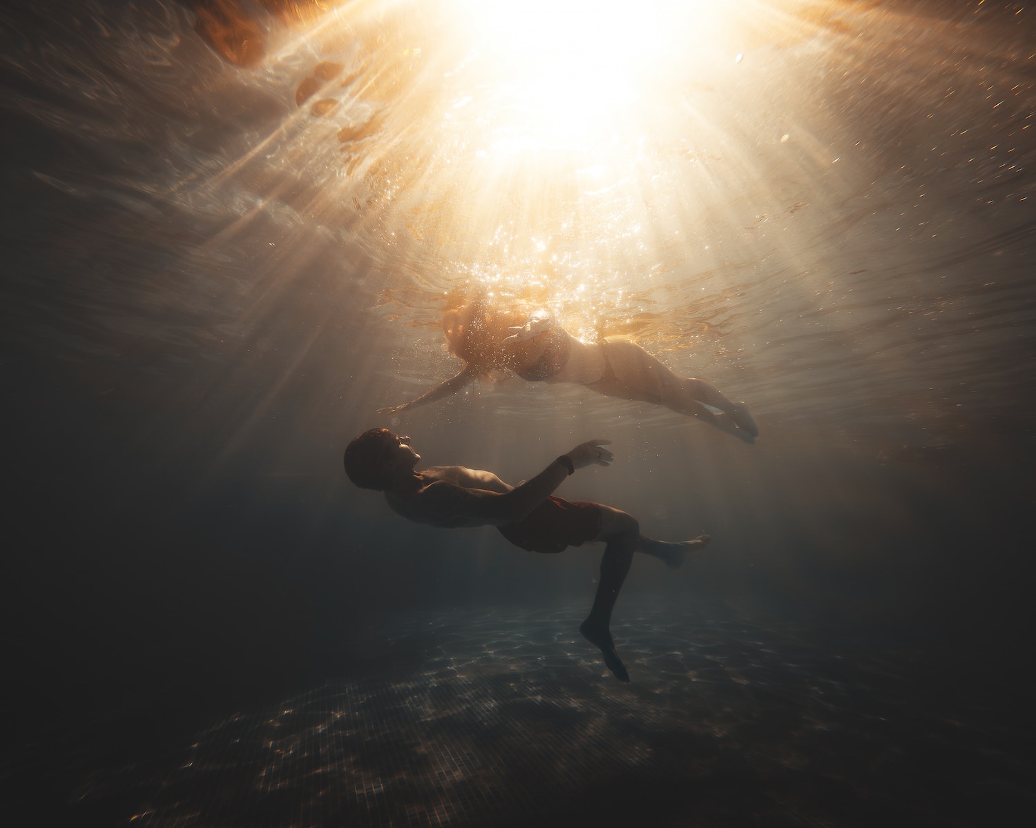 two people swimming in the water under the sun
